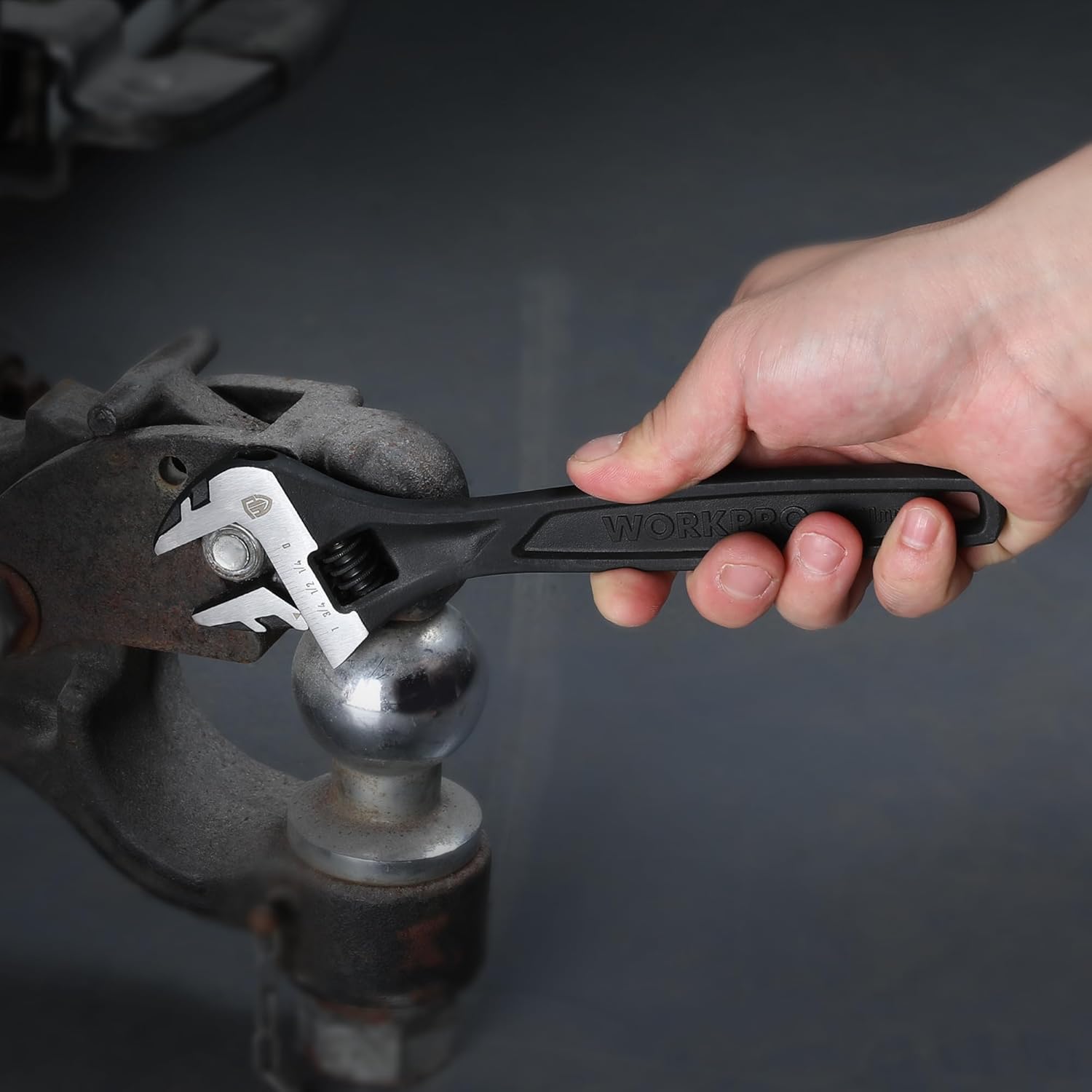Black oxide adjustable wrench held by hand adjusting a pipe fitting