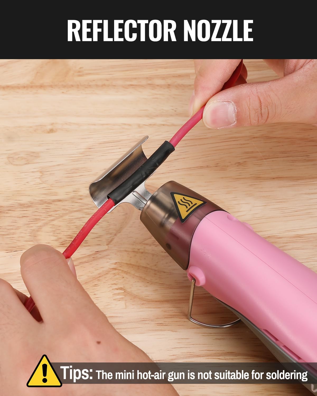 Pink mini cordless heat gun with reflector nozzle held near a wooden surface