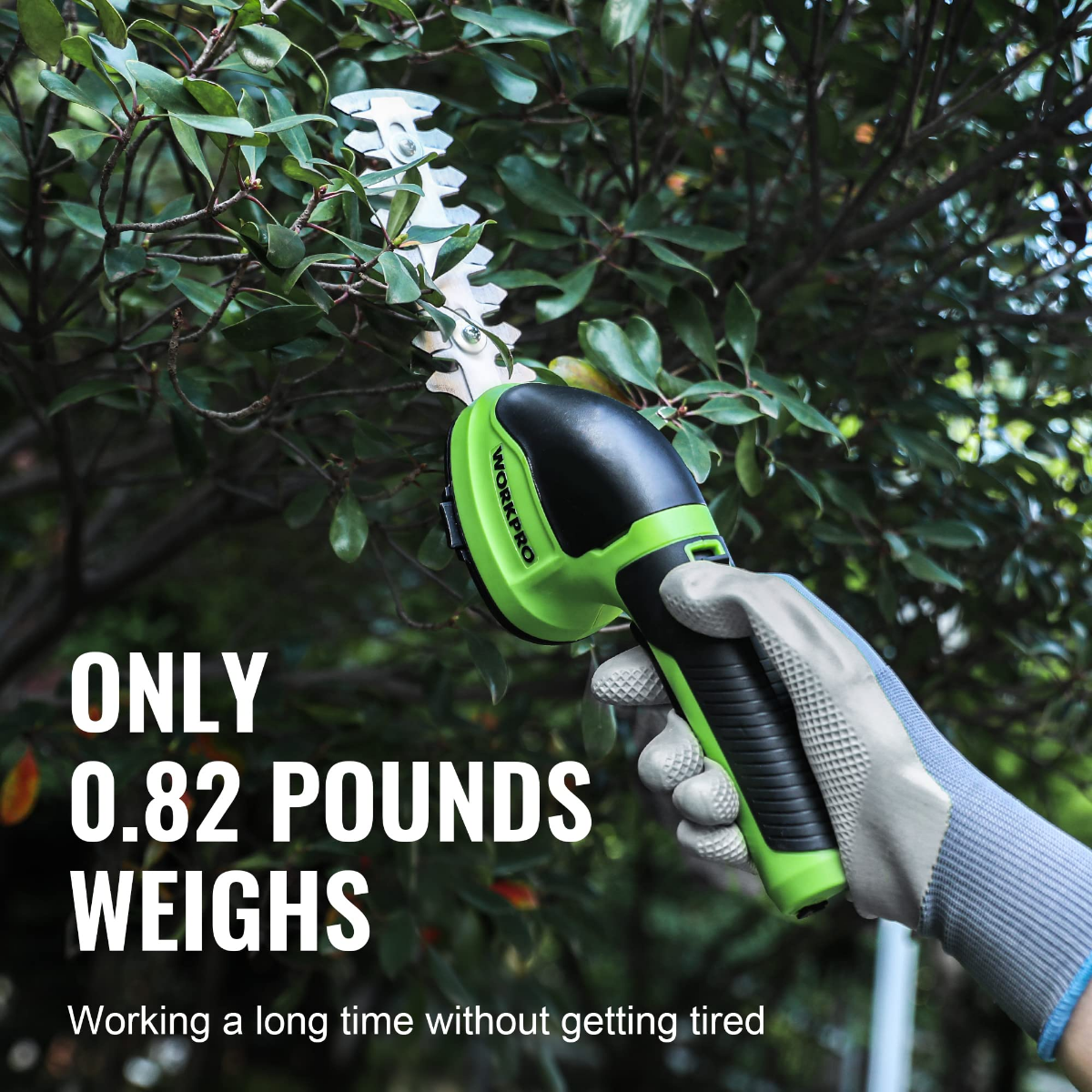 Green-and-black handheld electric trimmer held in a gloved hand near leafy branches