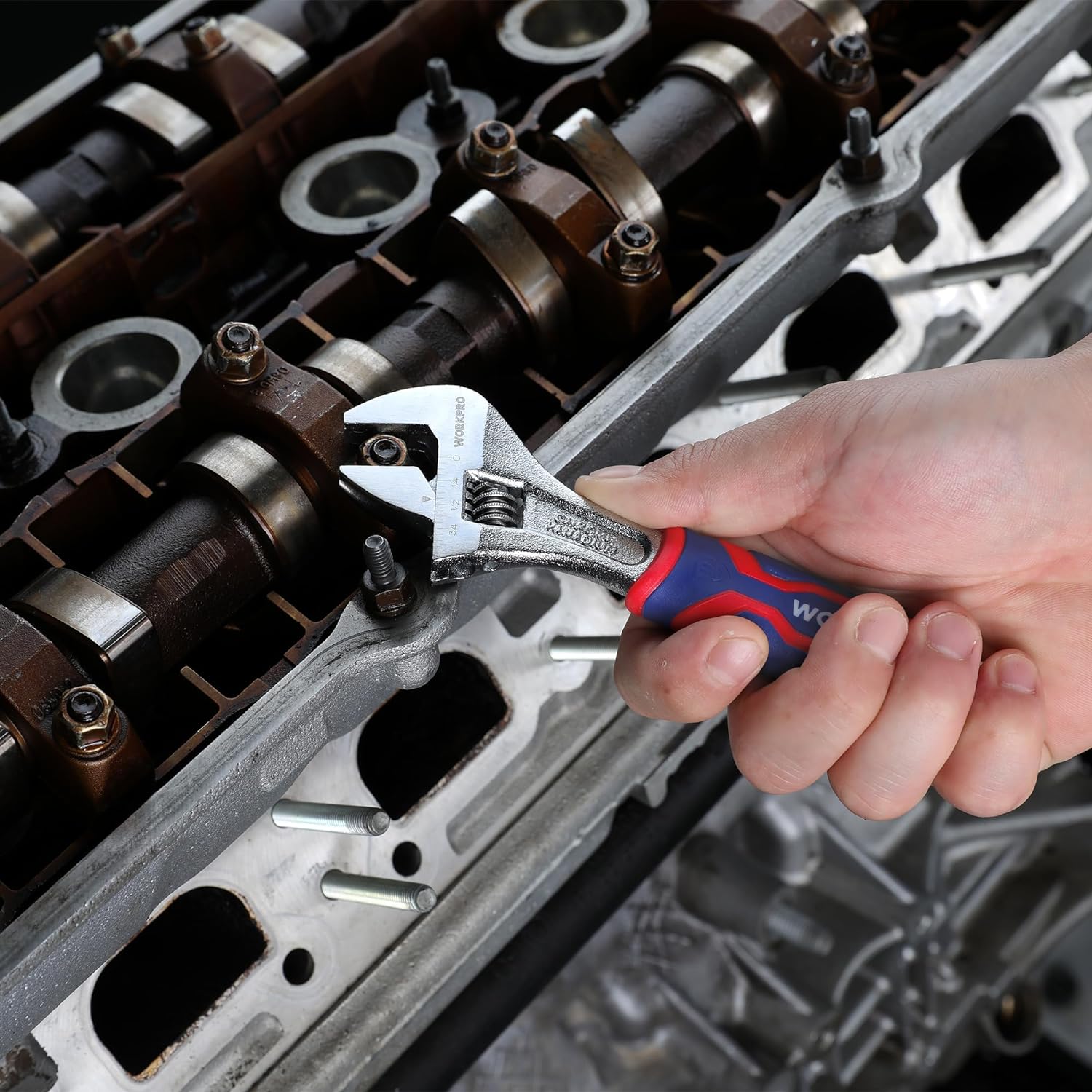 Adjustable wrench with blue/red grip in use on metal tool components