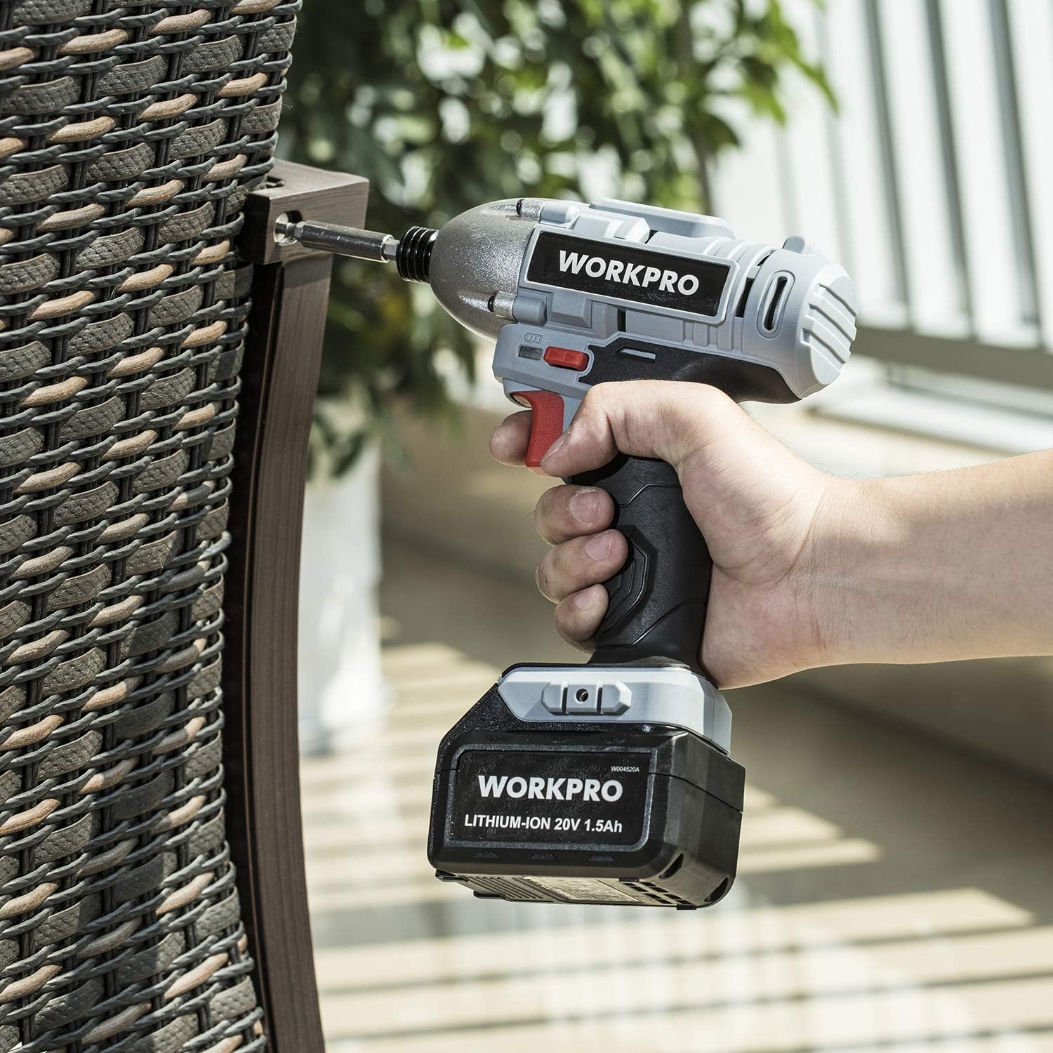WORKPRO cordless drill driving a hole into a fence with a hand grip and battery pack