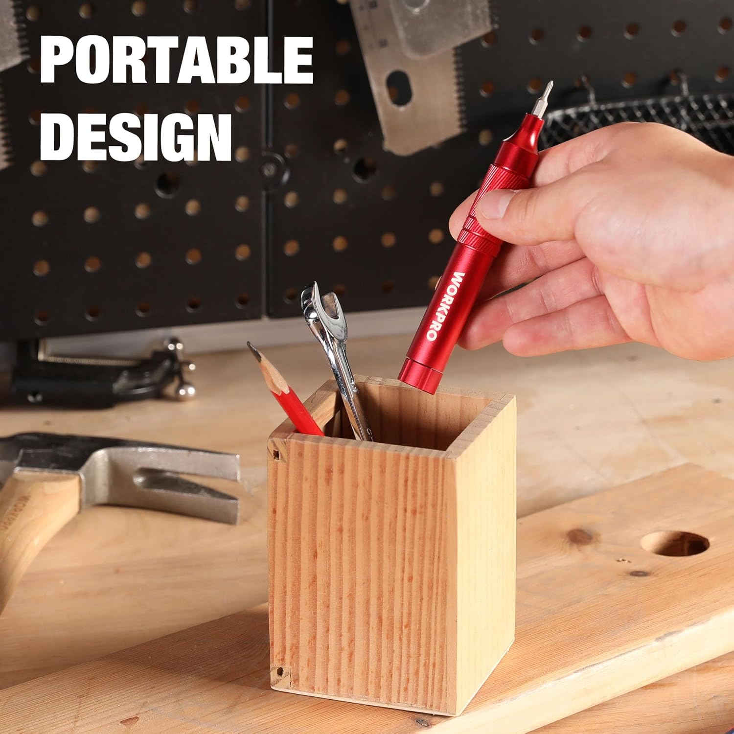 Red mini screwdriver in hand with bits near a wooden tool organizer