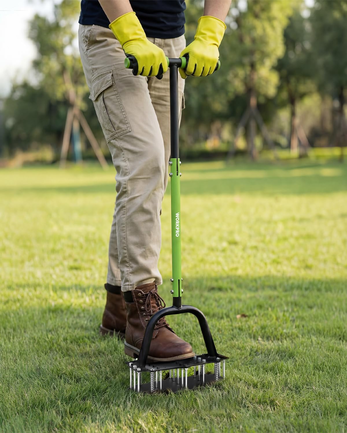 Manual lawn aerator tool on grass with green frame and black U-shaped handle