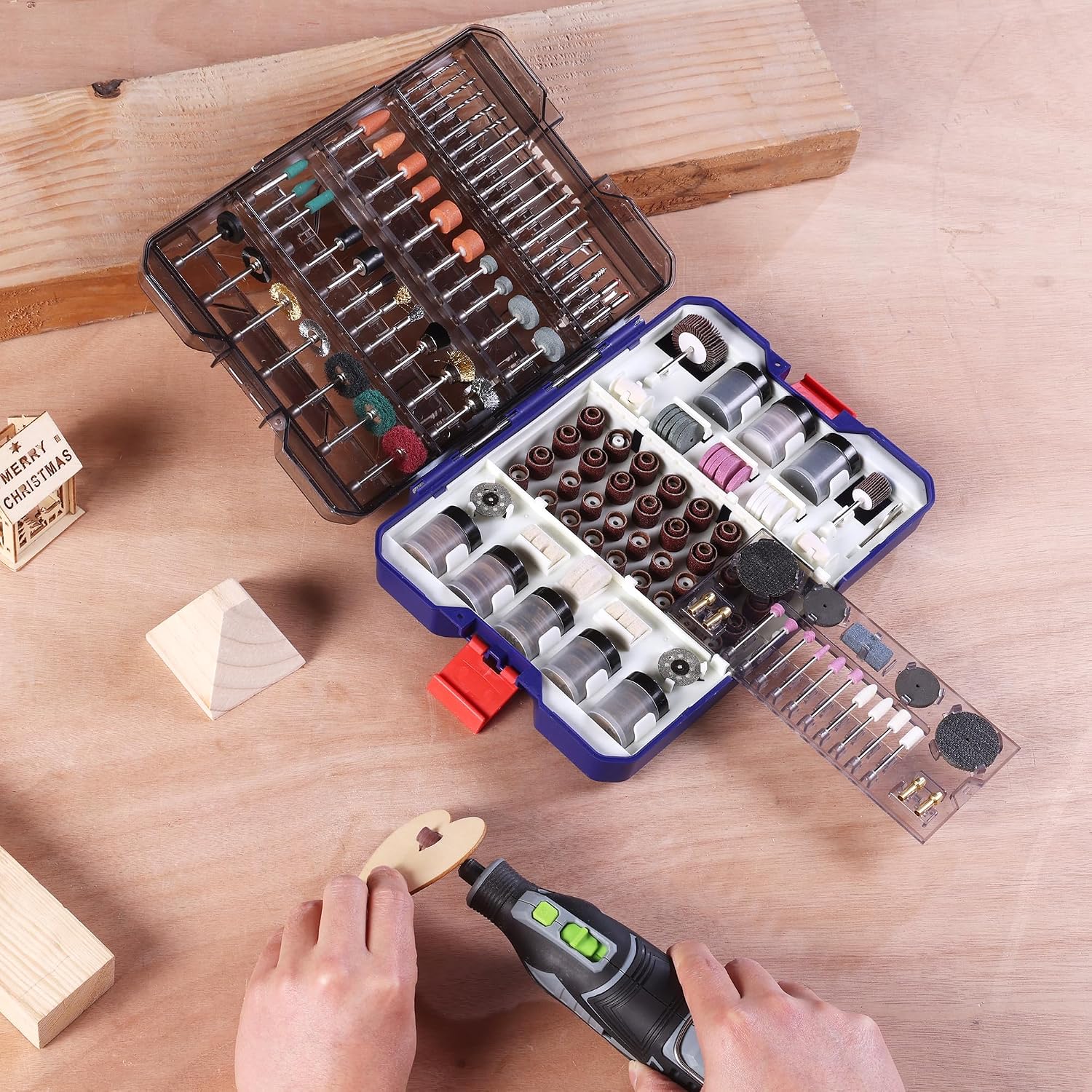 Rotary tool accessory kit with organized bits in open case on a wooden work surface