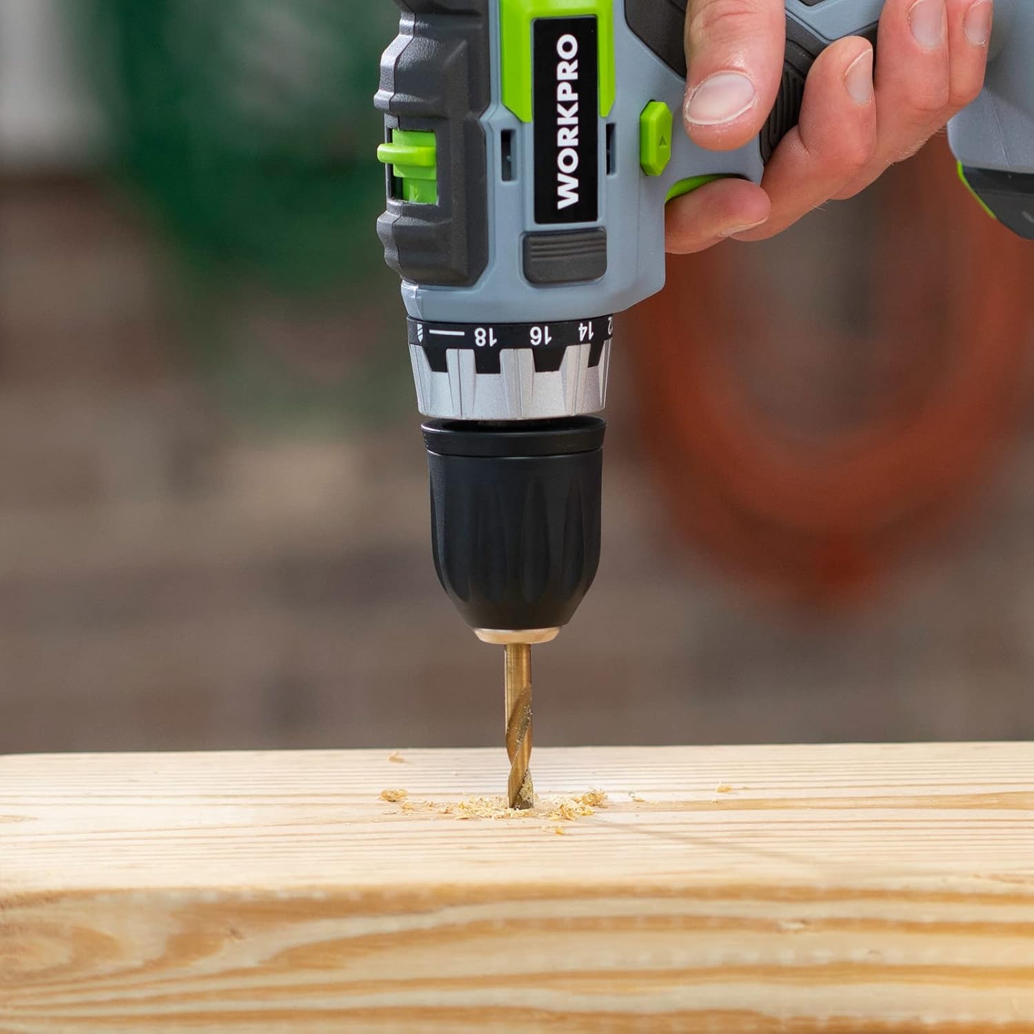 Handheld drill driving a gold hex shank bit into a wooden board