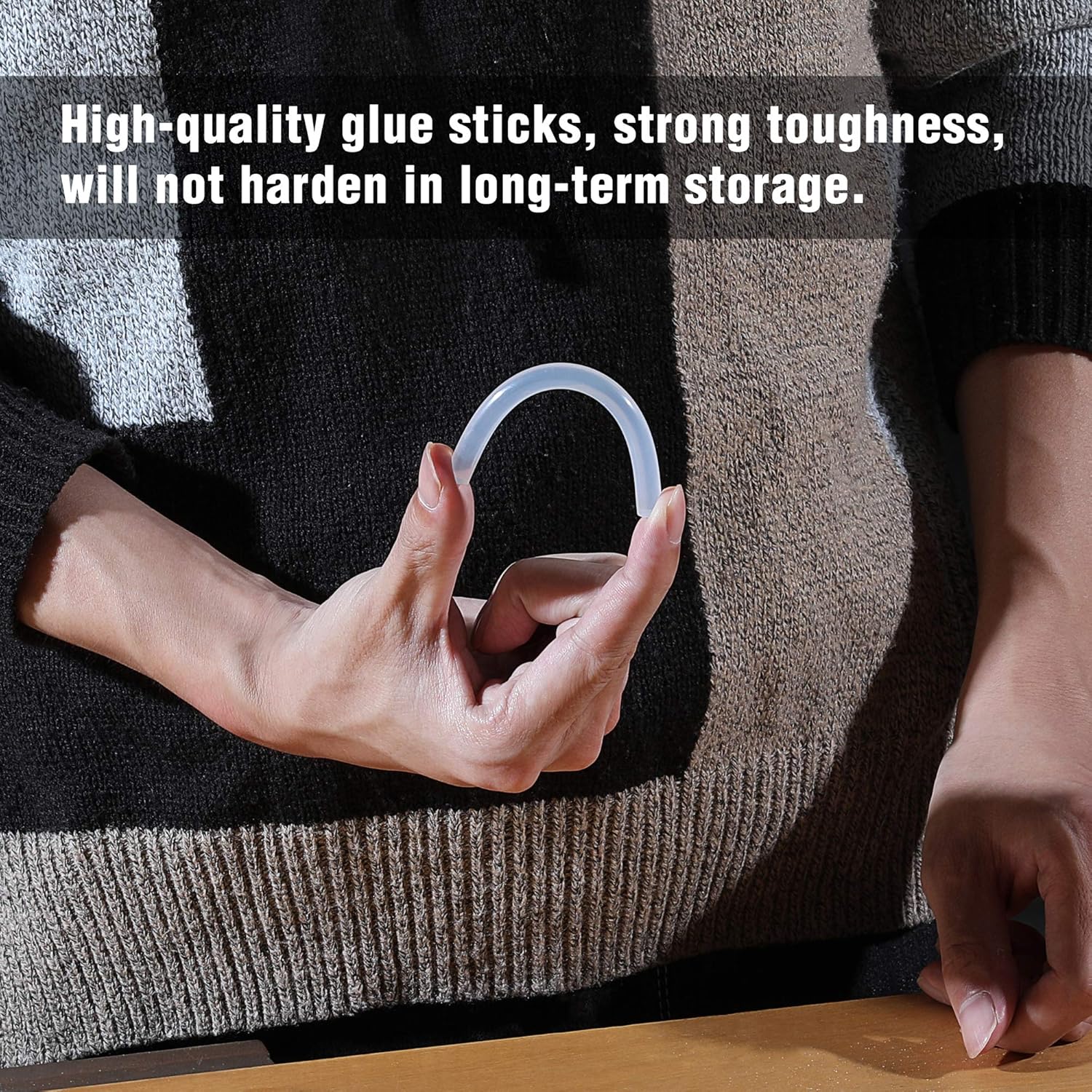 White hot glue sticks held by hands on sweater fabric, showing strong adhesive use