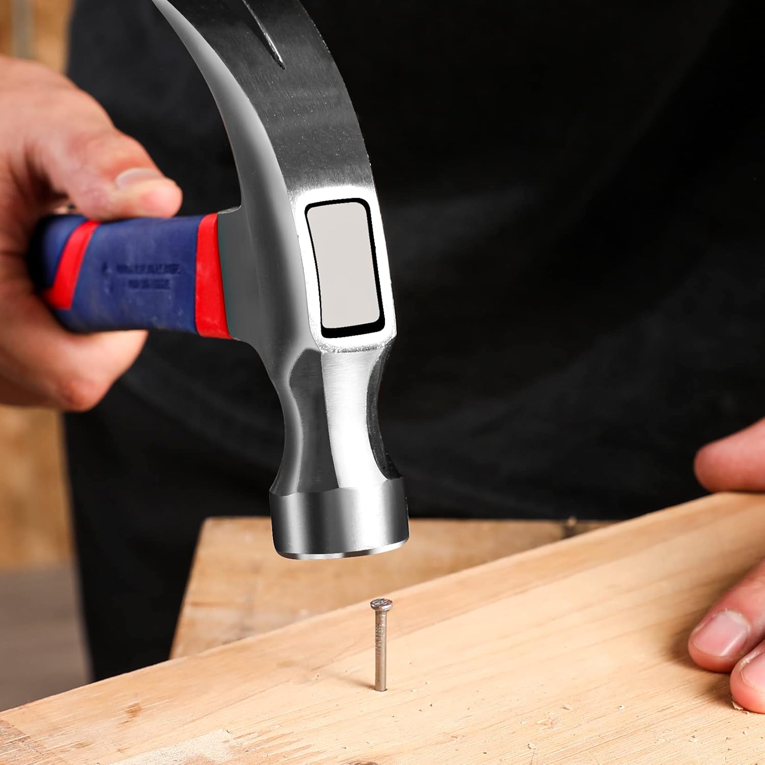 Claw hammer with steel head and blue-red fiberglass grip driving a screw into wood