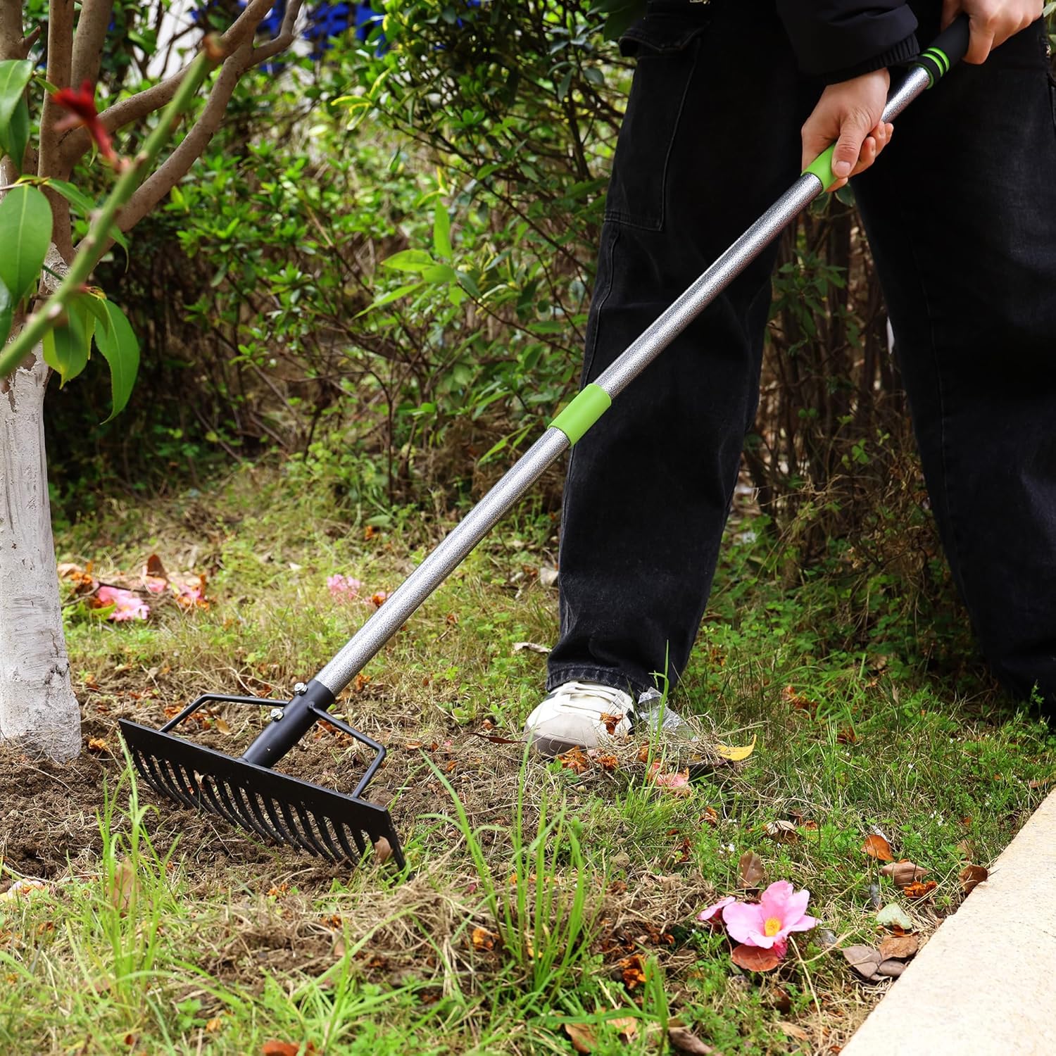 Bow rake loosening garden soil with 17 metal tines and green handle grip
