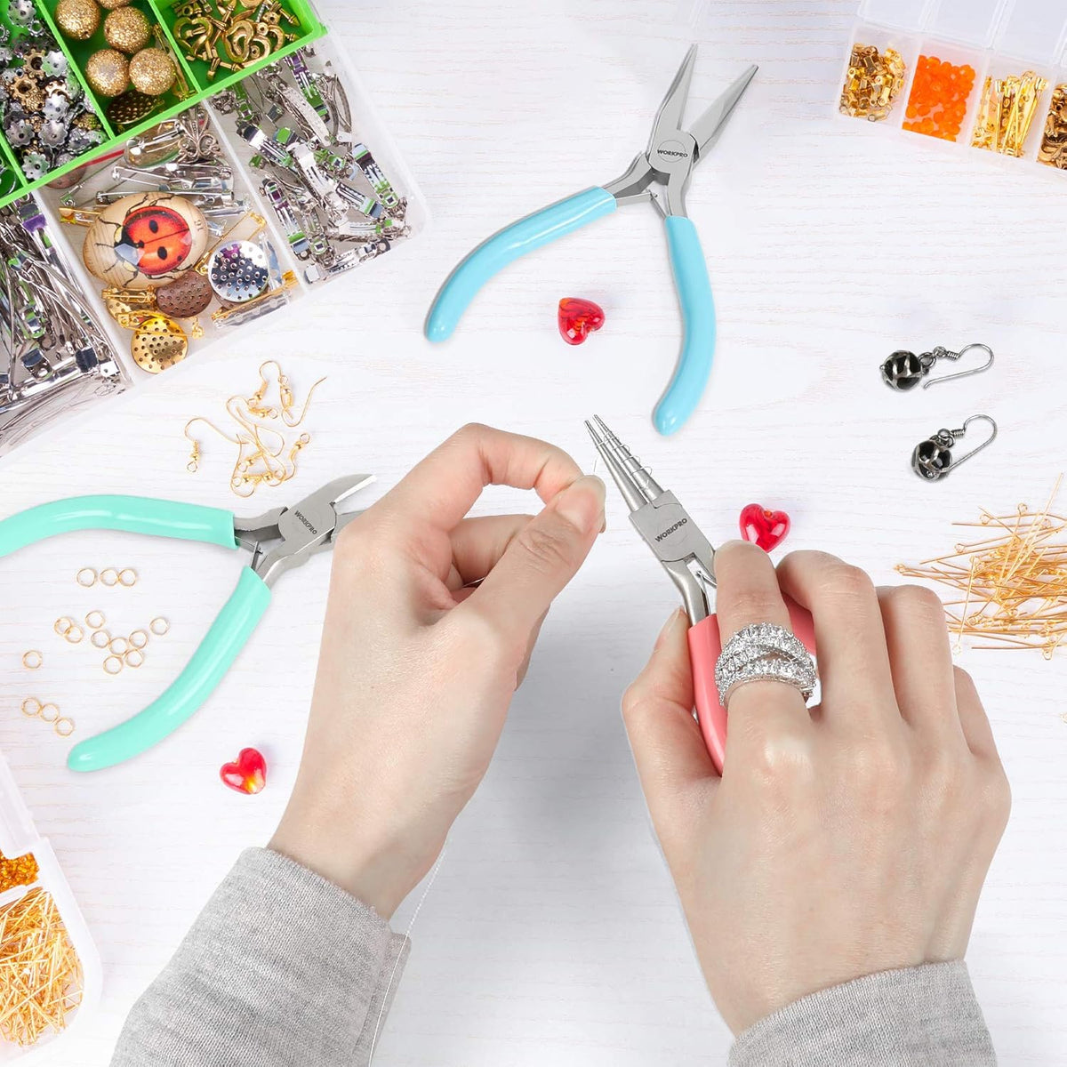 Hands assembling jewelry with needle-nose pliers and pink/teal handled tweezers