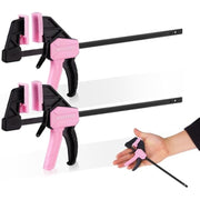 Pair of pink mini bar clamps attached to wood; release tool in hand for adjustment