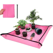 Pink foldable waterproof potting mat with black trim and button corners, set with plants