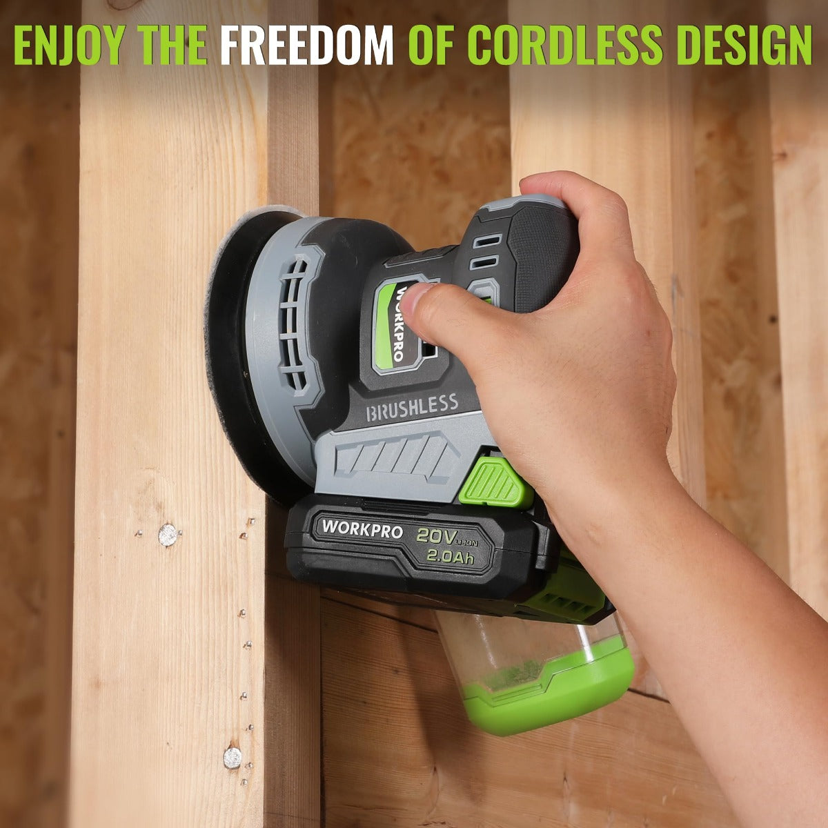 Cordless orbital sander with green battery pack pressed against a wooden board