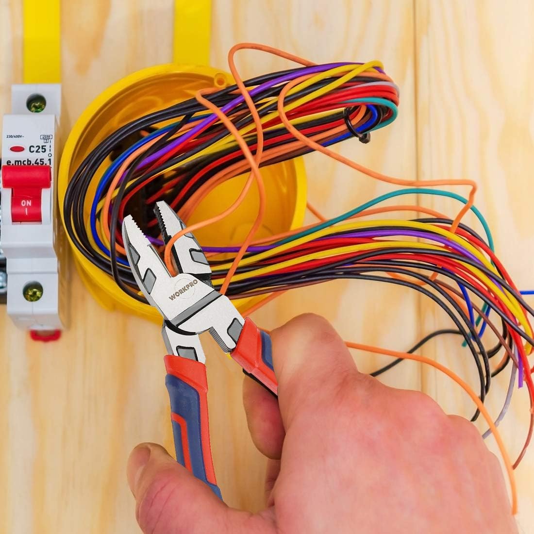 Linesman pliers in use near an electrical panel with bundled multicolored wires