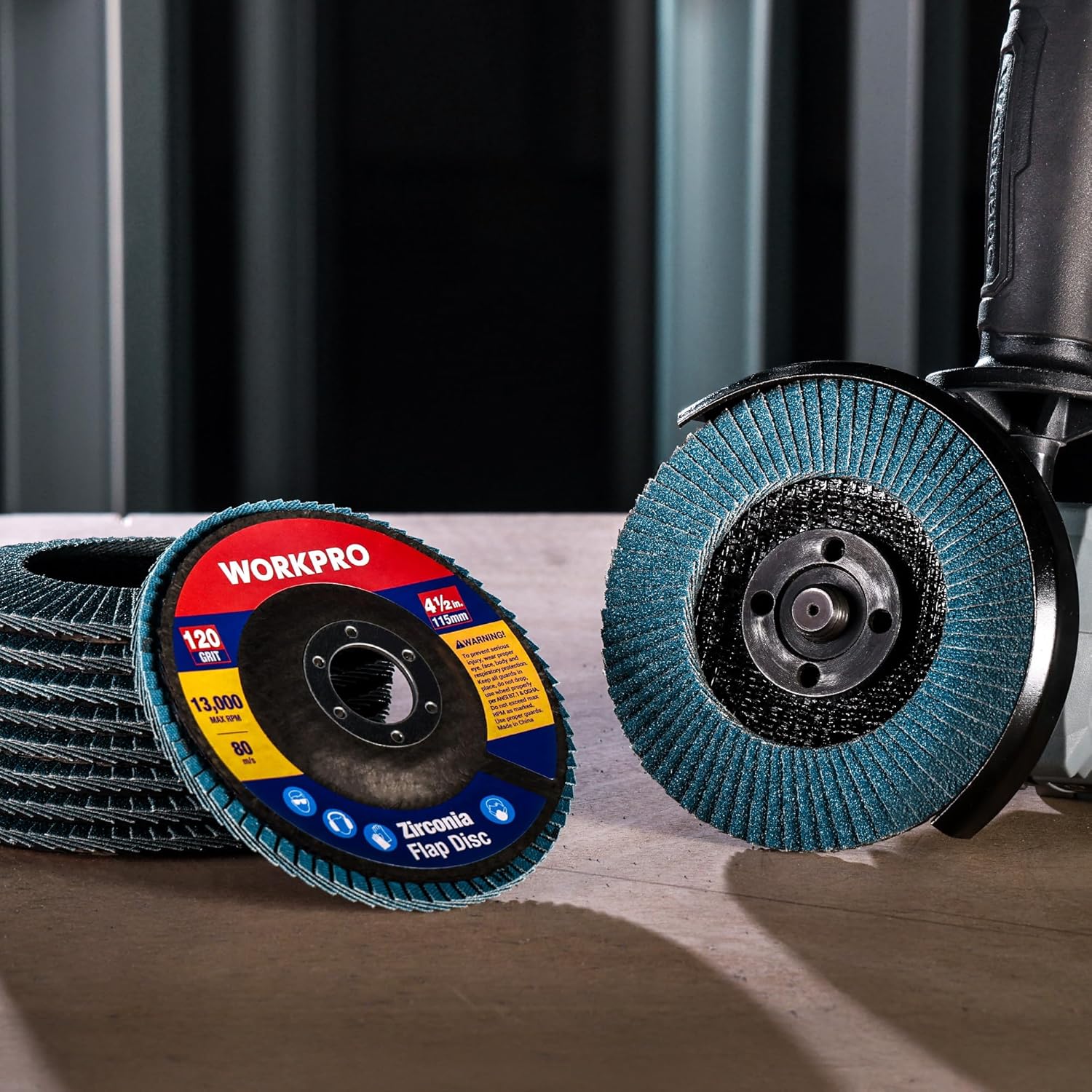 Blue zirconia flap discs with black abrasive surface on a workbench near a grinder