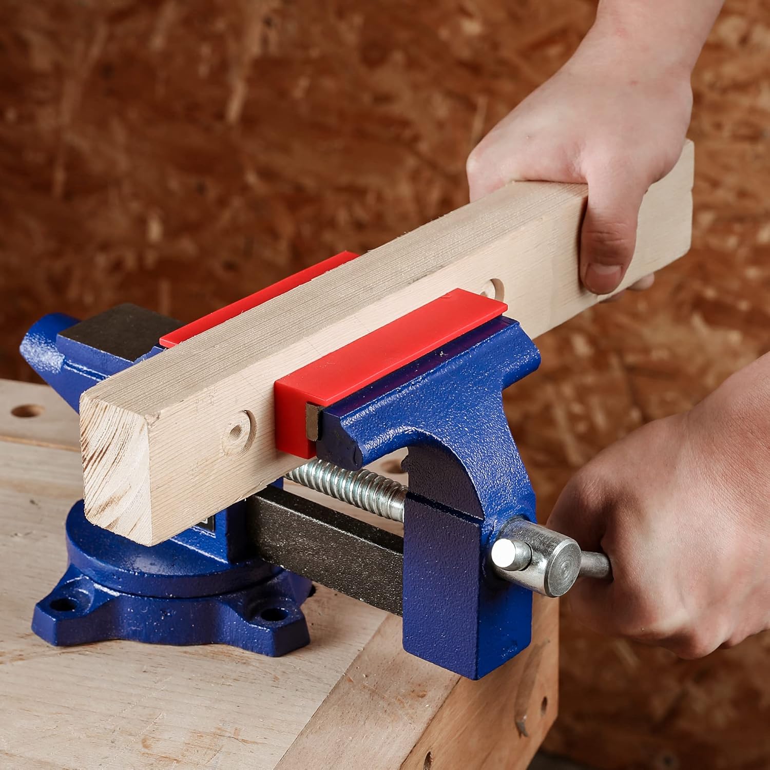 Magnetic vise jaw protective covers with red insert being fitted to a blue vise
