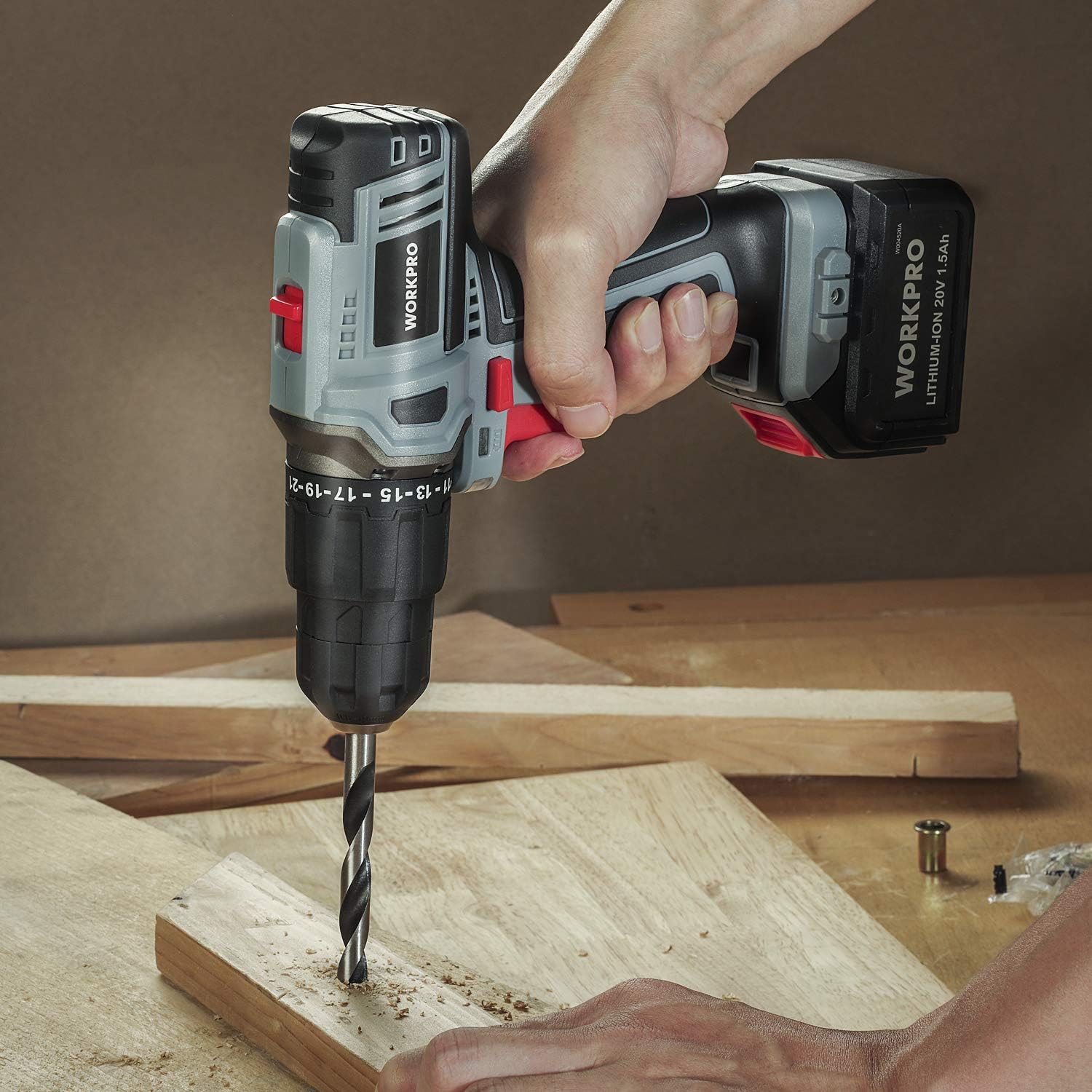 Hand holds WORKPRO cordless impact drill drilling into a wooden board