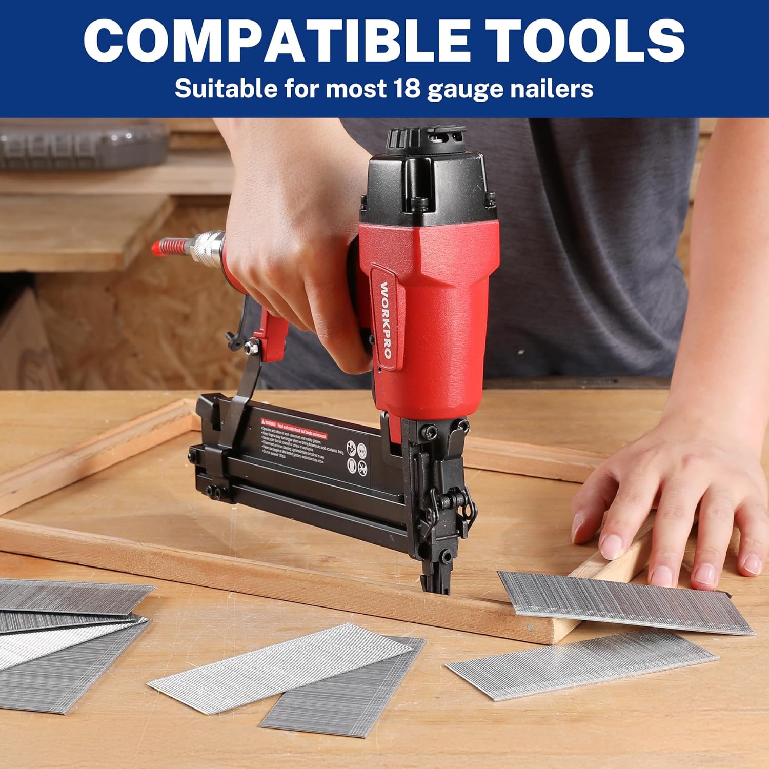 Silver brad nails laid out on a wooden board while a pneumatic nailer fires