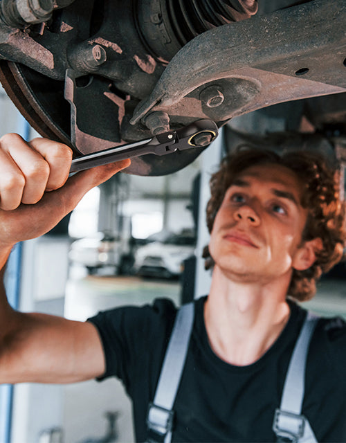 Mechanic using a wrench on a car suspension part, innovation and quality implied by tools in workshop
