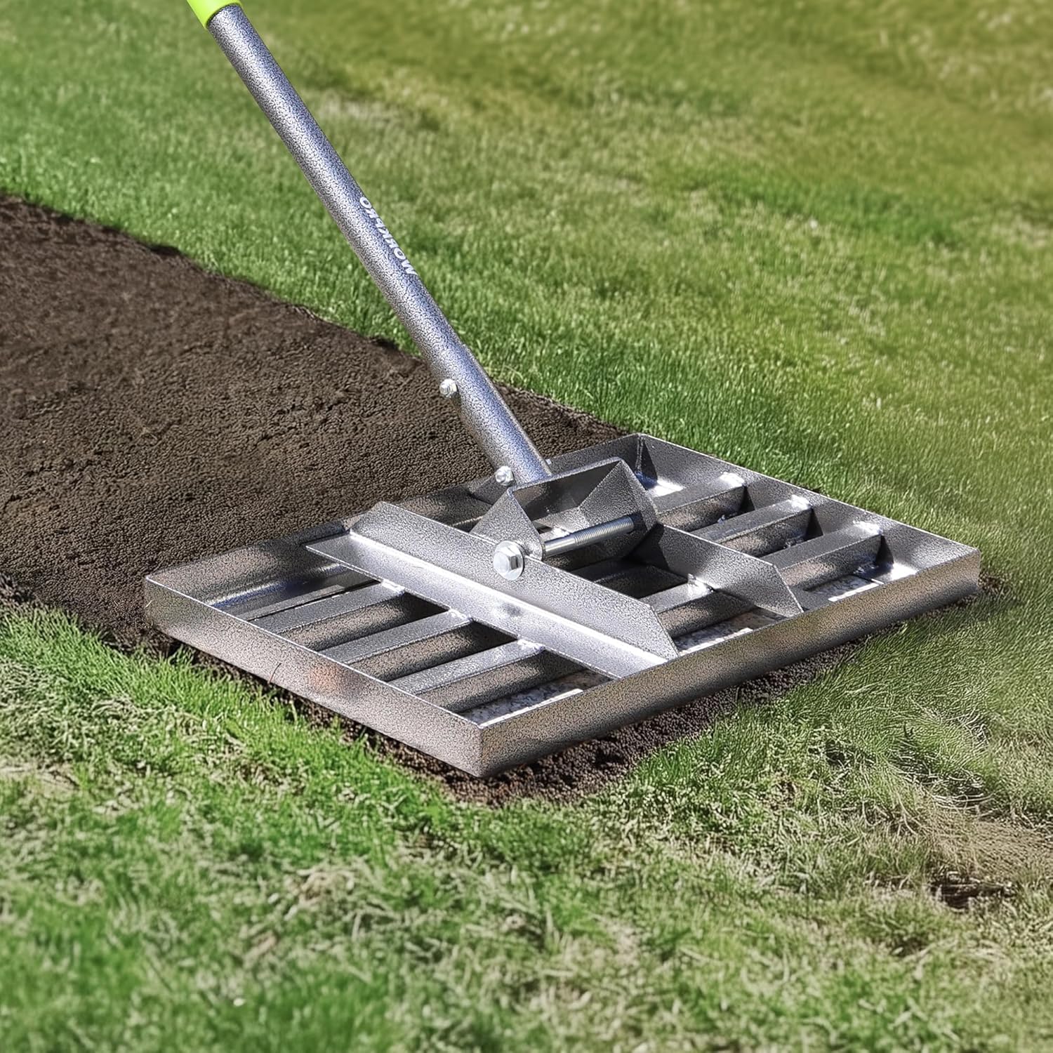 Metal lawn leveling rake head with bolts on soil and grass edge