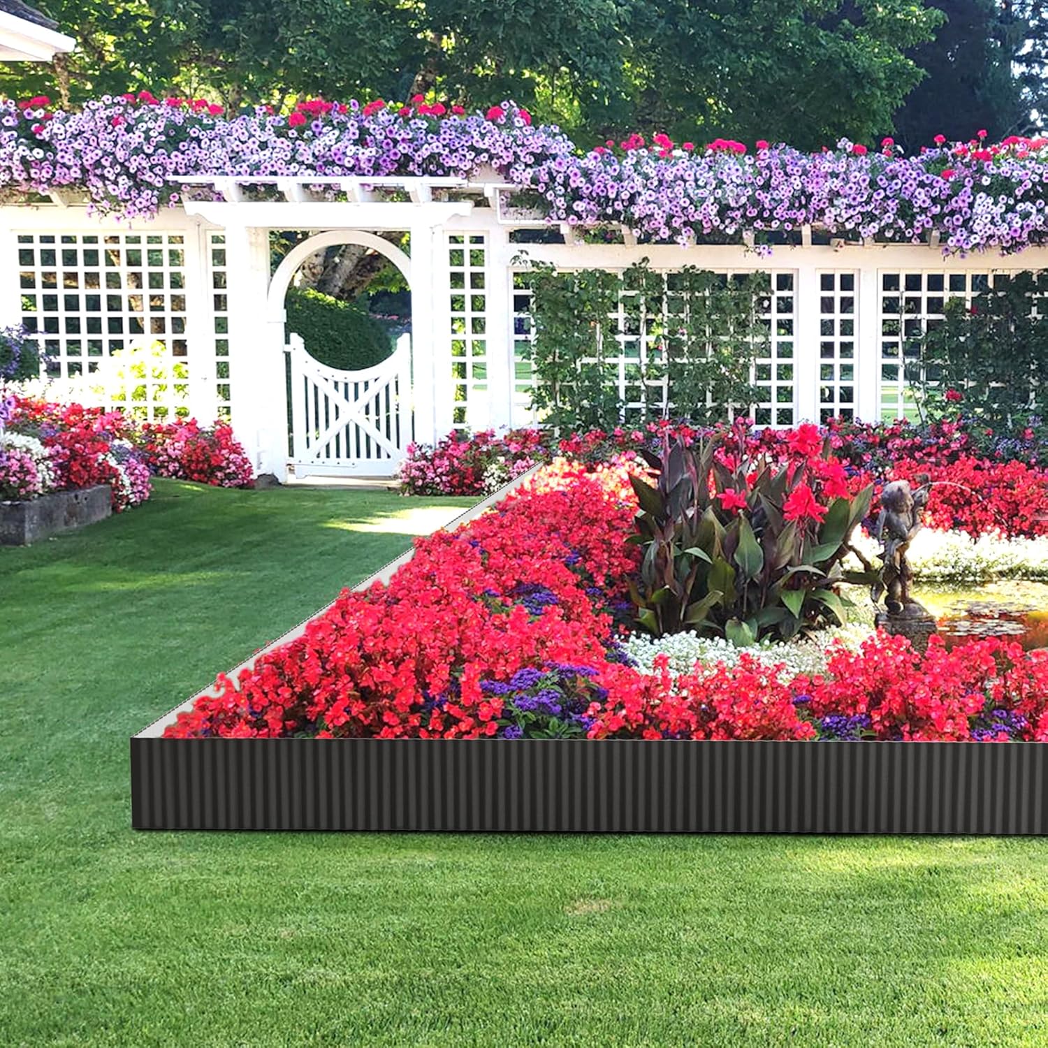 Black metal edging strip bordering a large flower bed along a garden walkway.