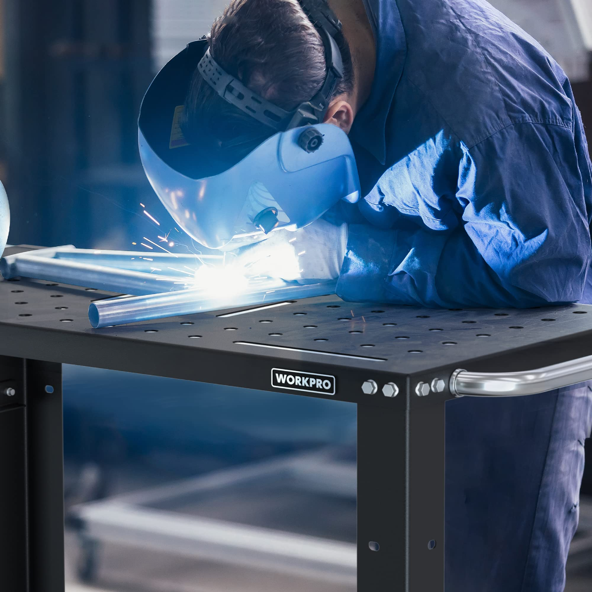 Welding table with perforated steel top and curved side handle, shown in close-up