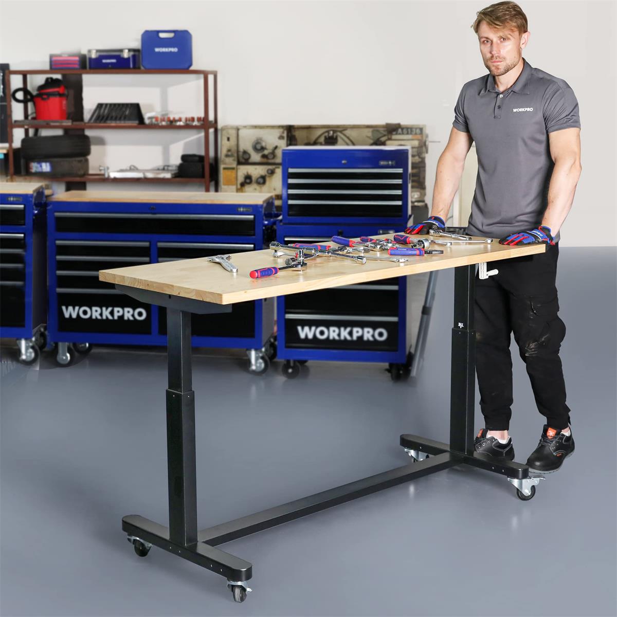 Height-adjustable work table with light wood top, black steel base, casters and crank handle.