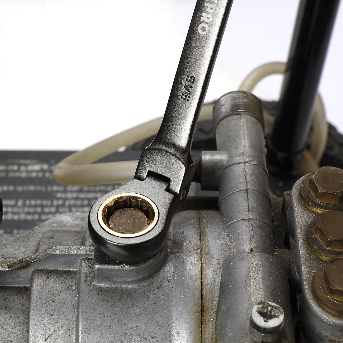 Ratcheting flex-head combination wrench gripping a fastener on metal surface