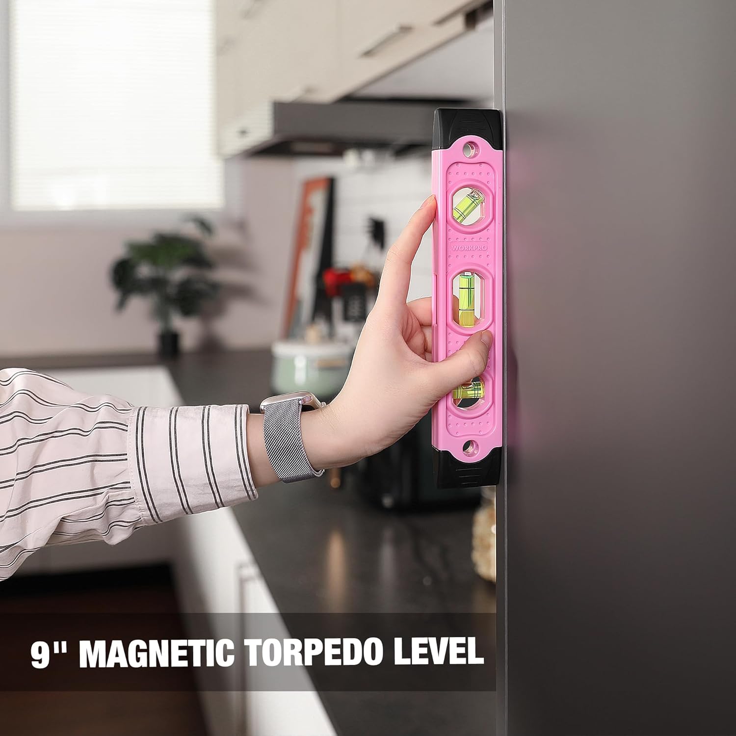 Pink magnetic torpedo level held in hand with bubble vial