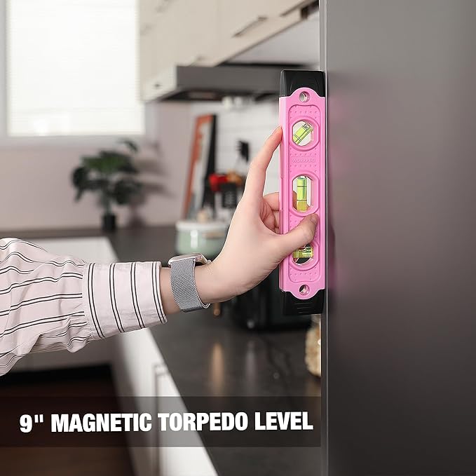 Pink magnetic torpedo level held on a cabinet for straight DIY measurements.