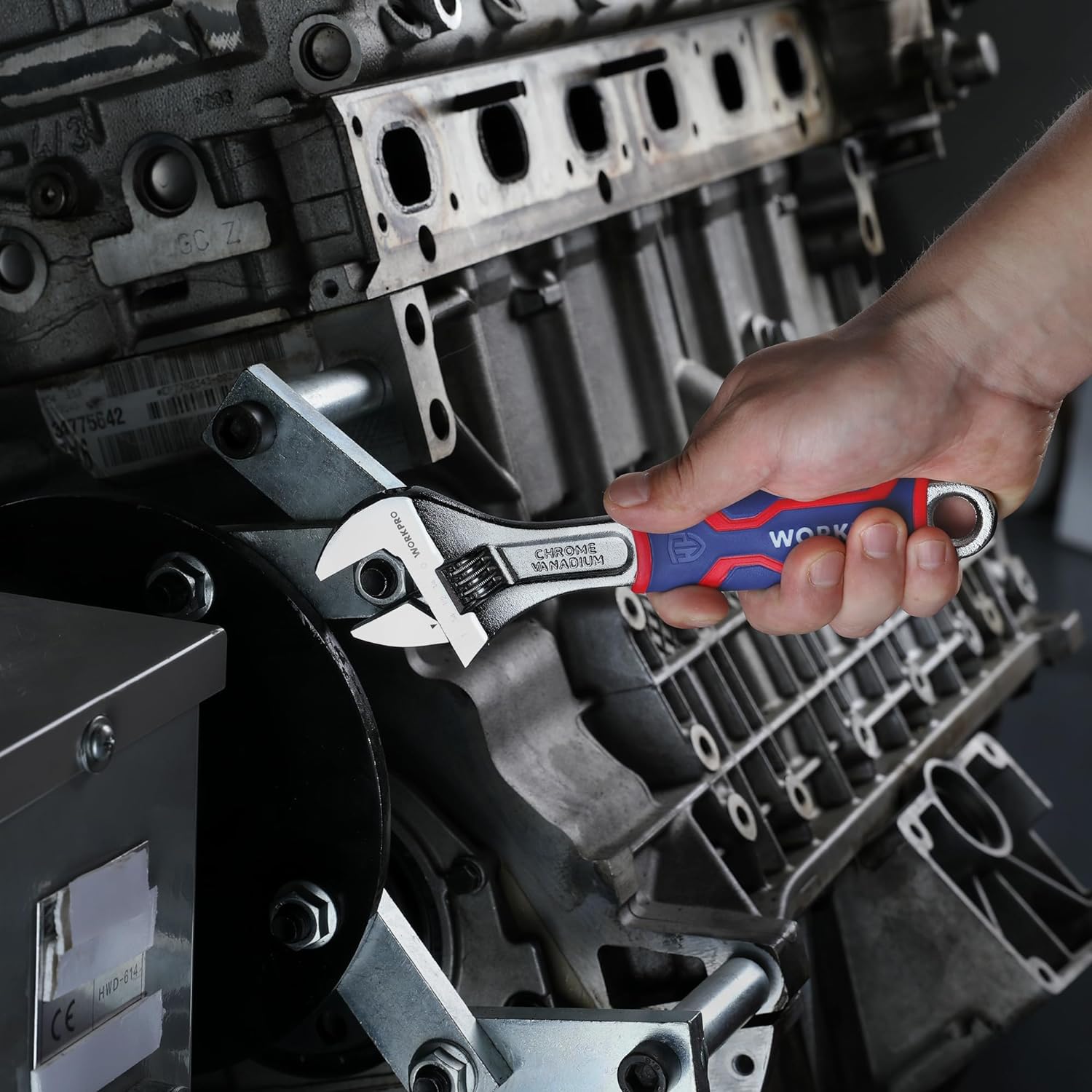 Adjustable wrench with blue/red grip tightening hardware on engine parts
