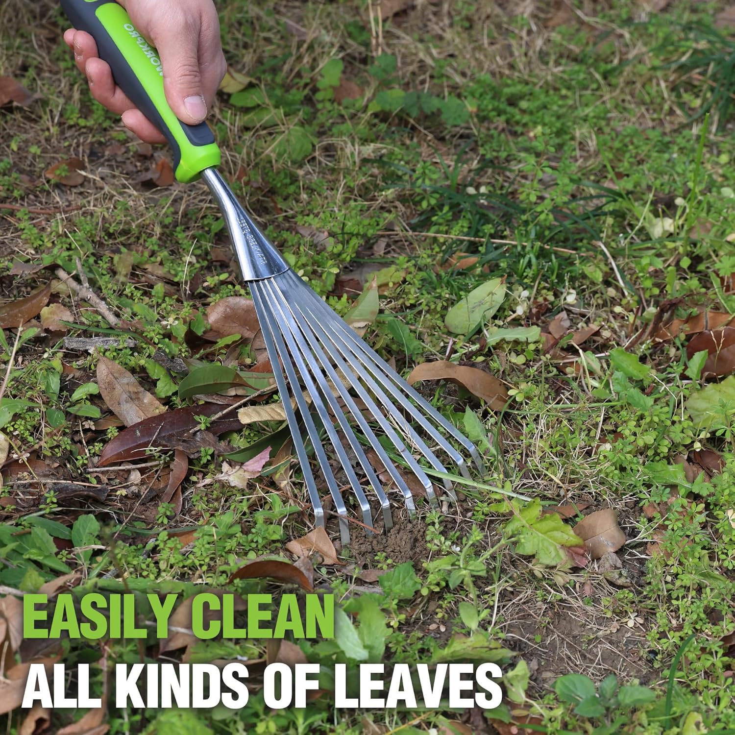 Garden hand rake with stainless tines and green soft grip handle in soil