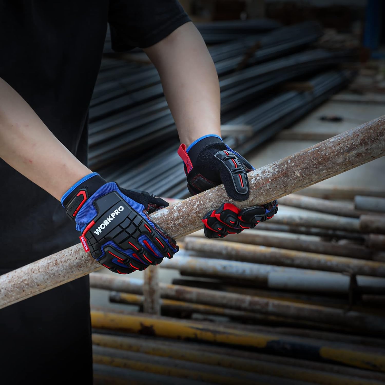 Pair of black work gloves gripping metal rebar with textured non-slip palms and red trim