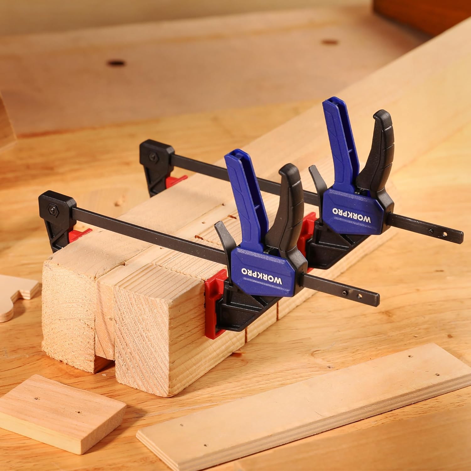 WORKPRO mini bar clamps holding stacked lumber on a workbench