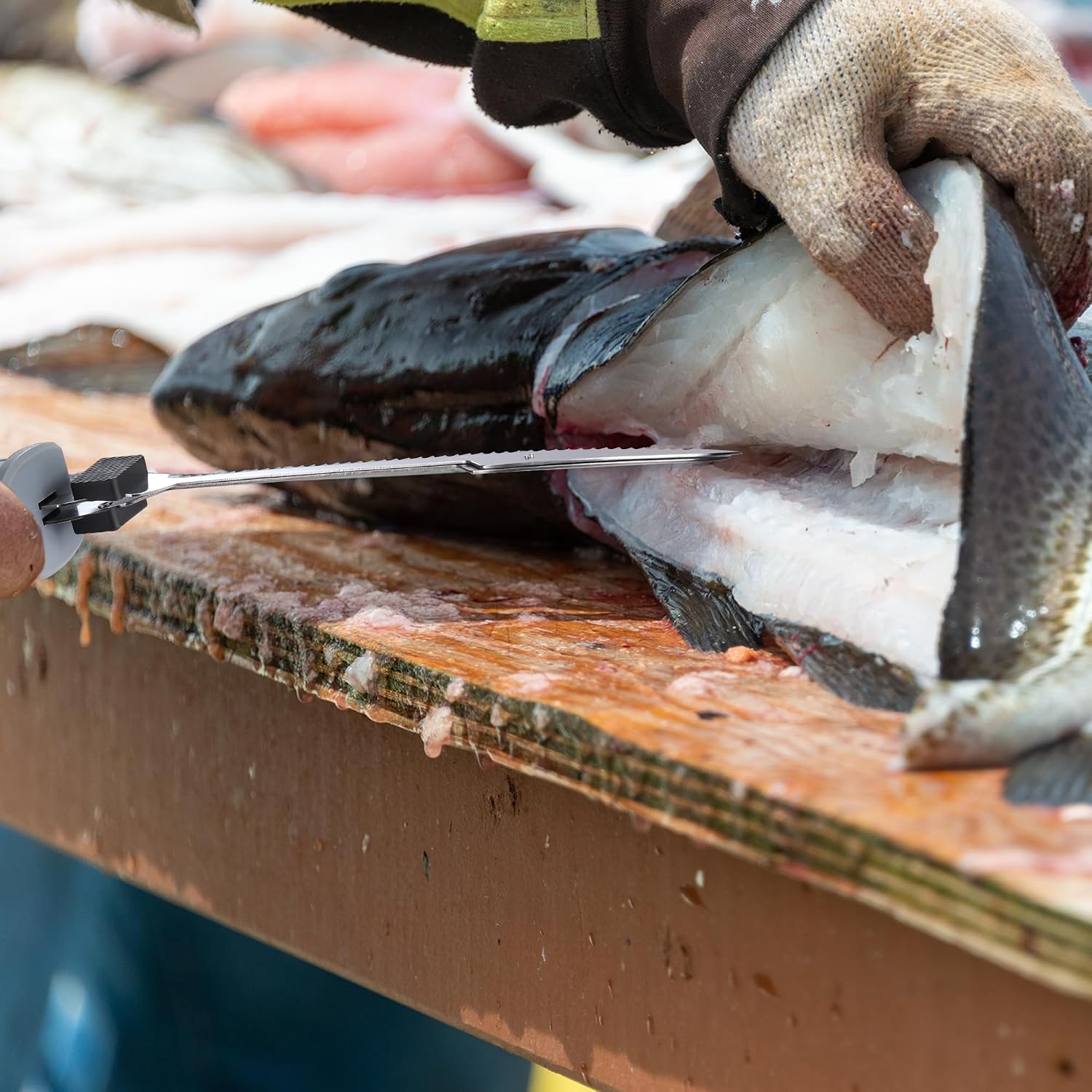 Serrated fillet knife replacement blade cutting fish on a wooden surface