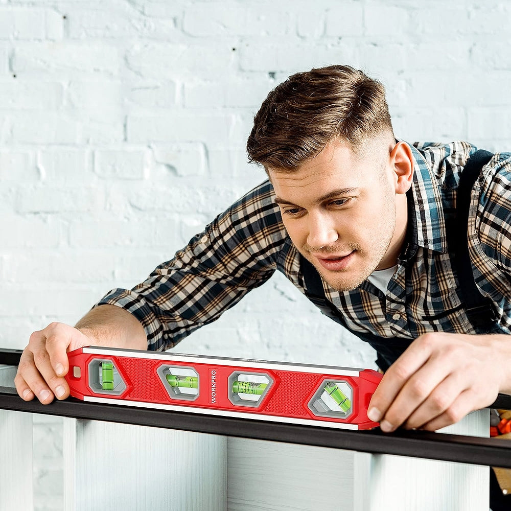 Compact red torpedo level with 4 green bubble vials held against a metal surface