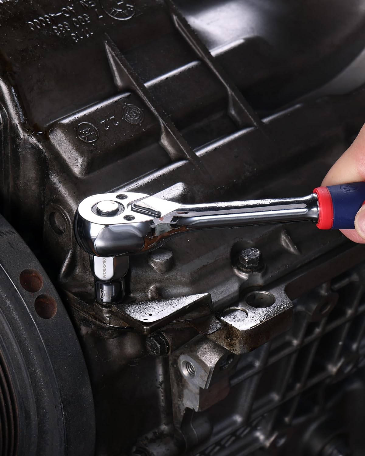 Chrome socket and ratchet tool in use on a metal automotive fitting