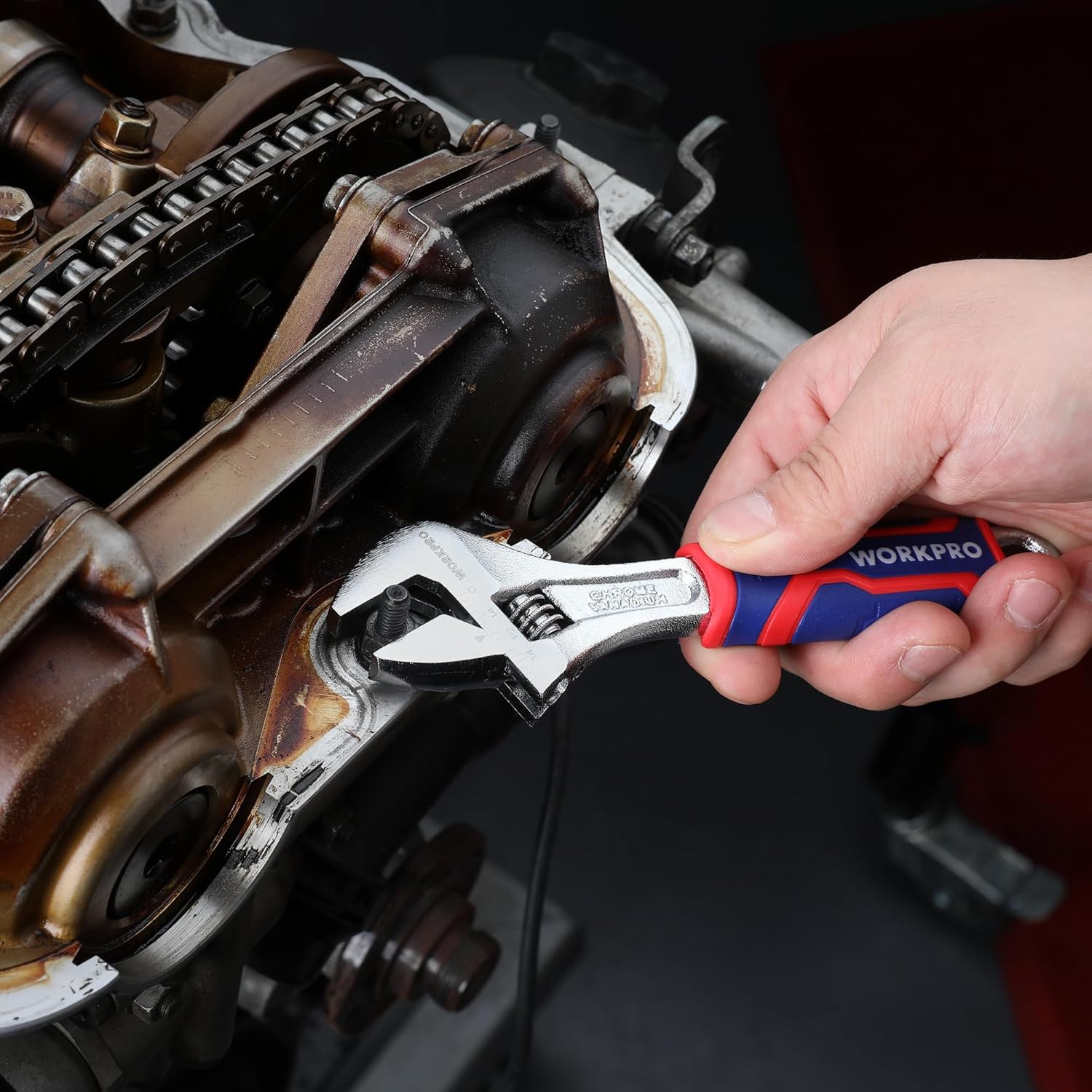 Adjustable wrench in use on machinery with red/blue anti-slip grip