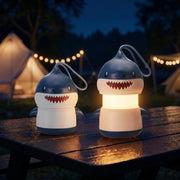 Two blue shark-shaped kids lanterns with white bellies and loop lanyards, warm glow