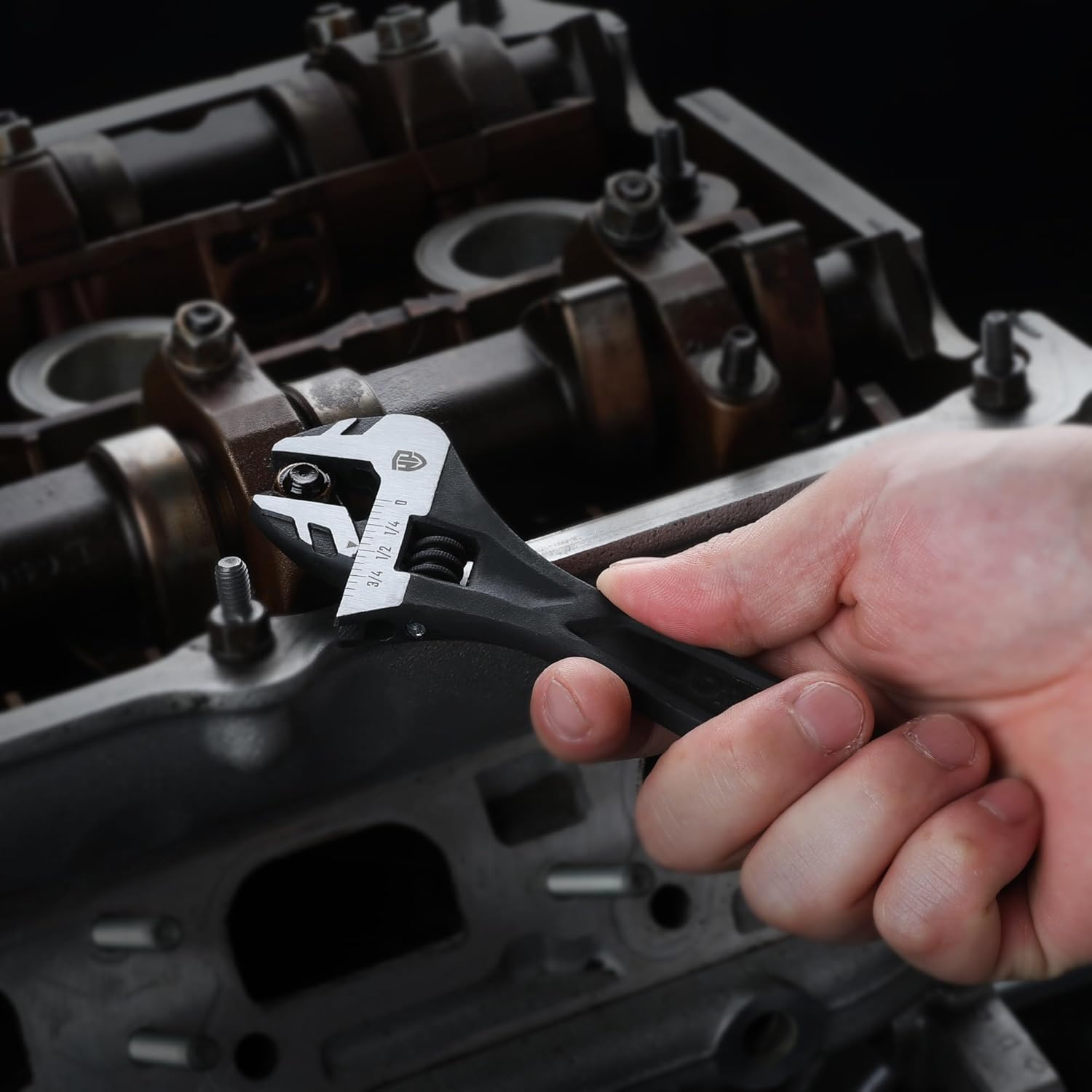 Black adjustable wrench held over equipment, showing open jaw and knurled adjuster.