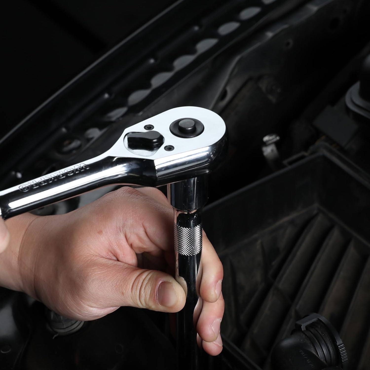 Chrome ratchet wrench held in hand, knurled grip and reversible head visible