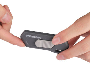 Gray ceramic safety box cutter with hand sliding blade into housing
