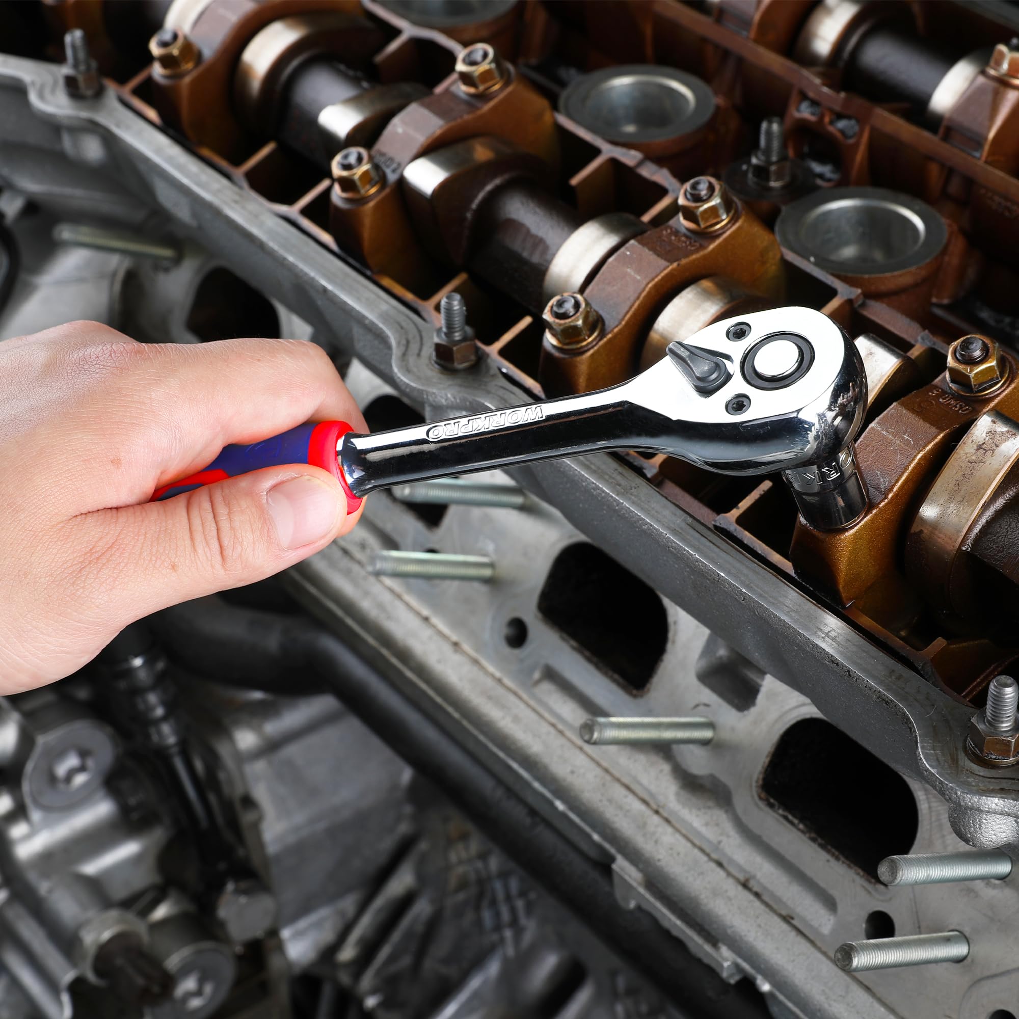 Hand using a chrome ratchet with red-blue handle in a metal engine compartment