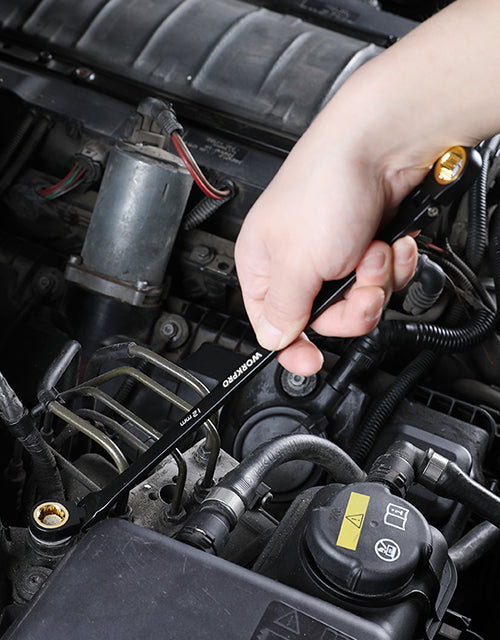 Hand adjusting an engine component in a car bay, with visible wiring and hoses for quality and secure fit
