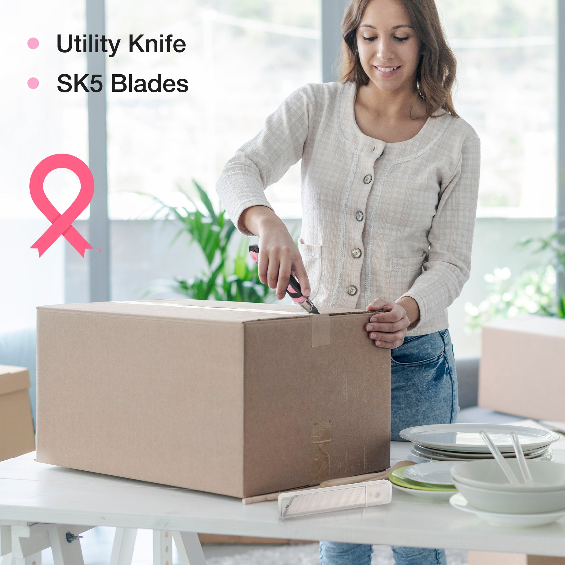 Pink utility knife cutting a cardboard box; DIY tool kit accessory in use.