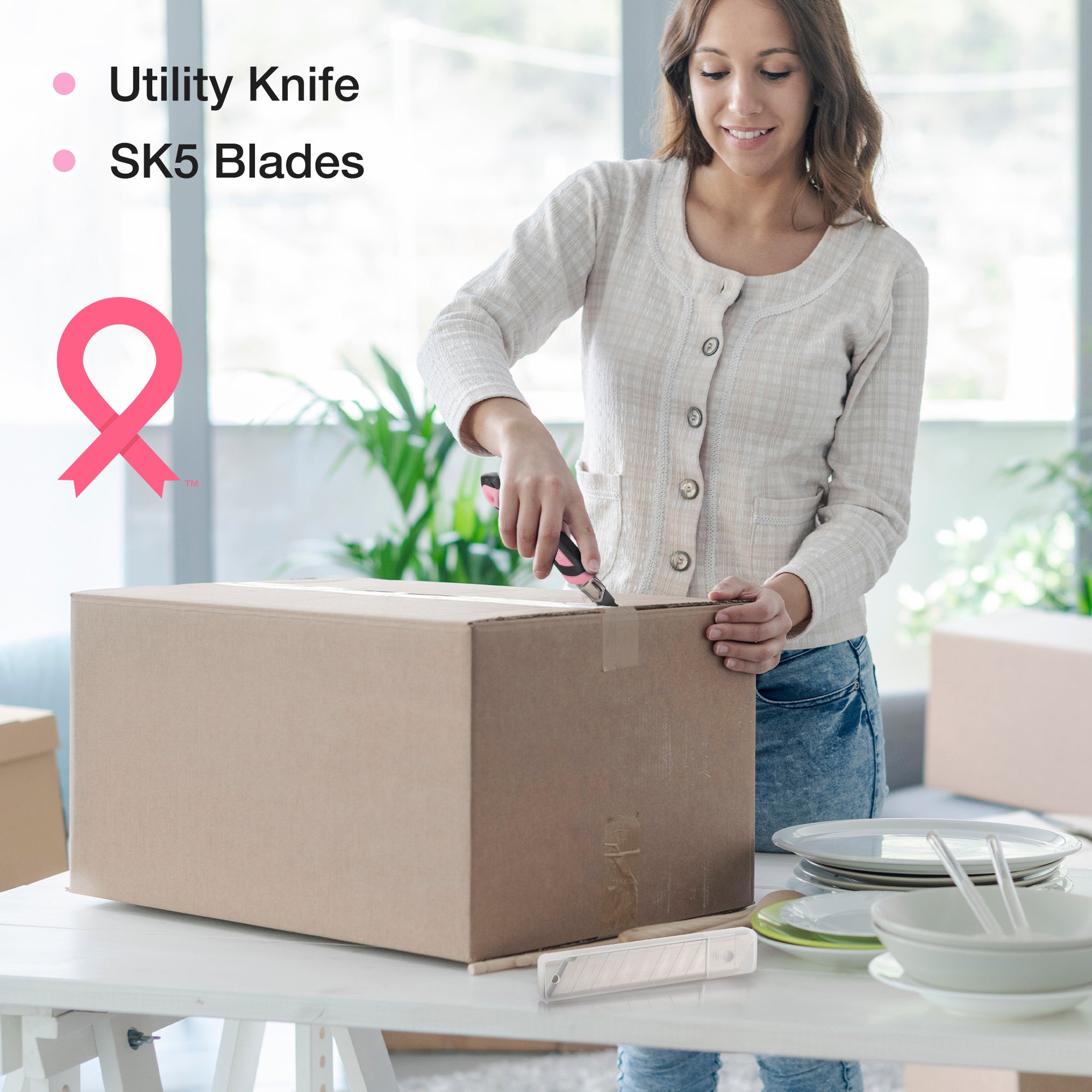 Pink utility knife cutting a cardboard box; DIY tool kit accessory in use.