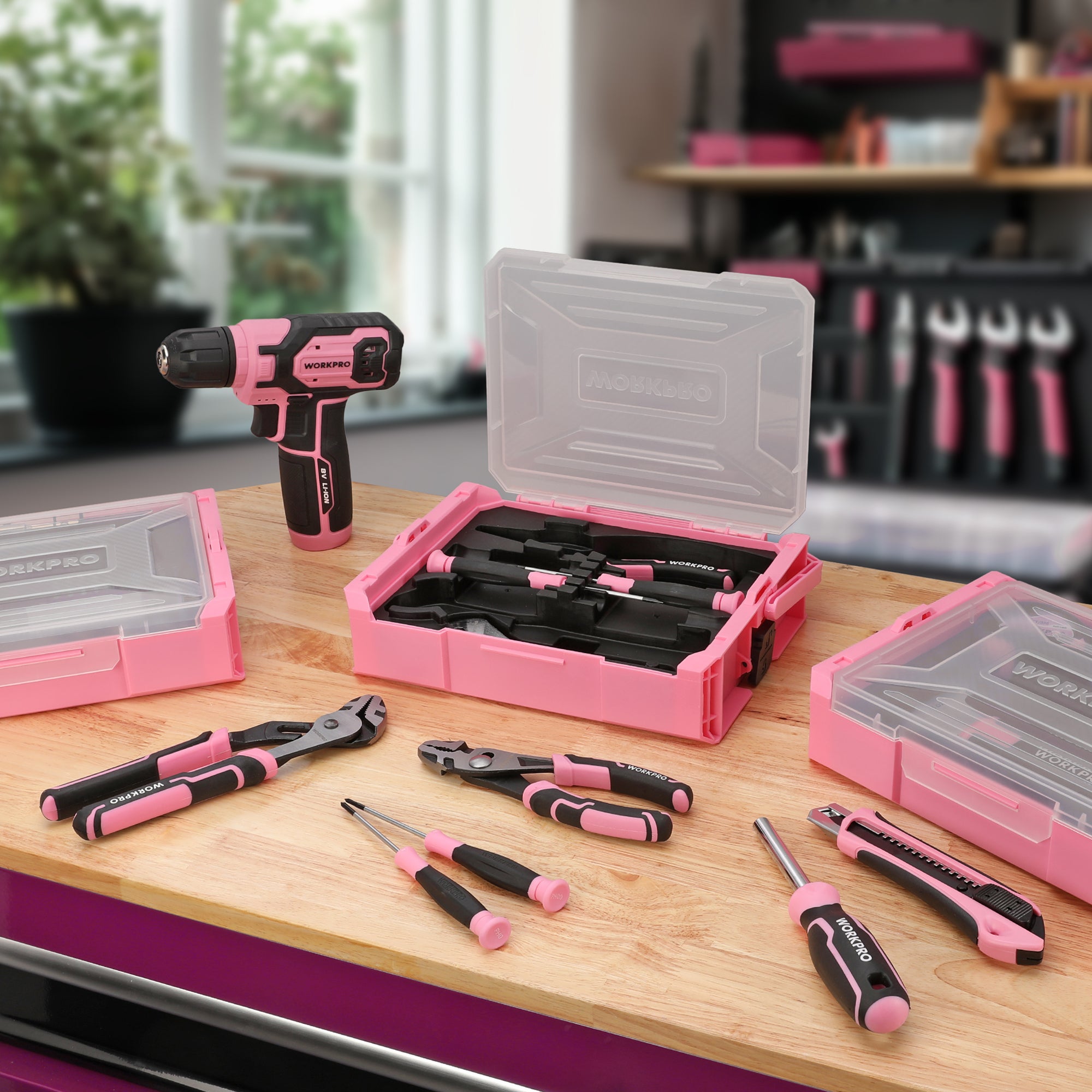 Pink tool kit with open stackable storage boxes and assorted hand tools on workbench