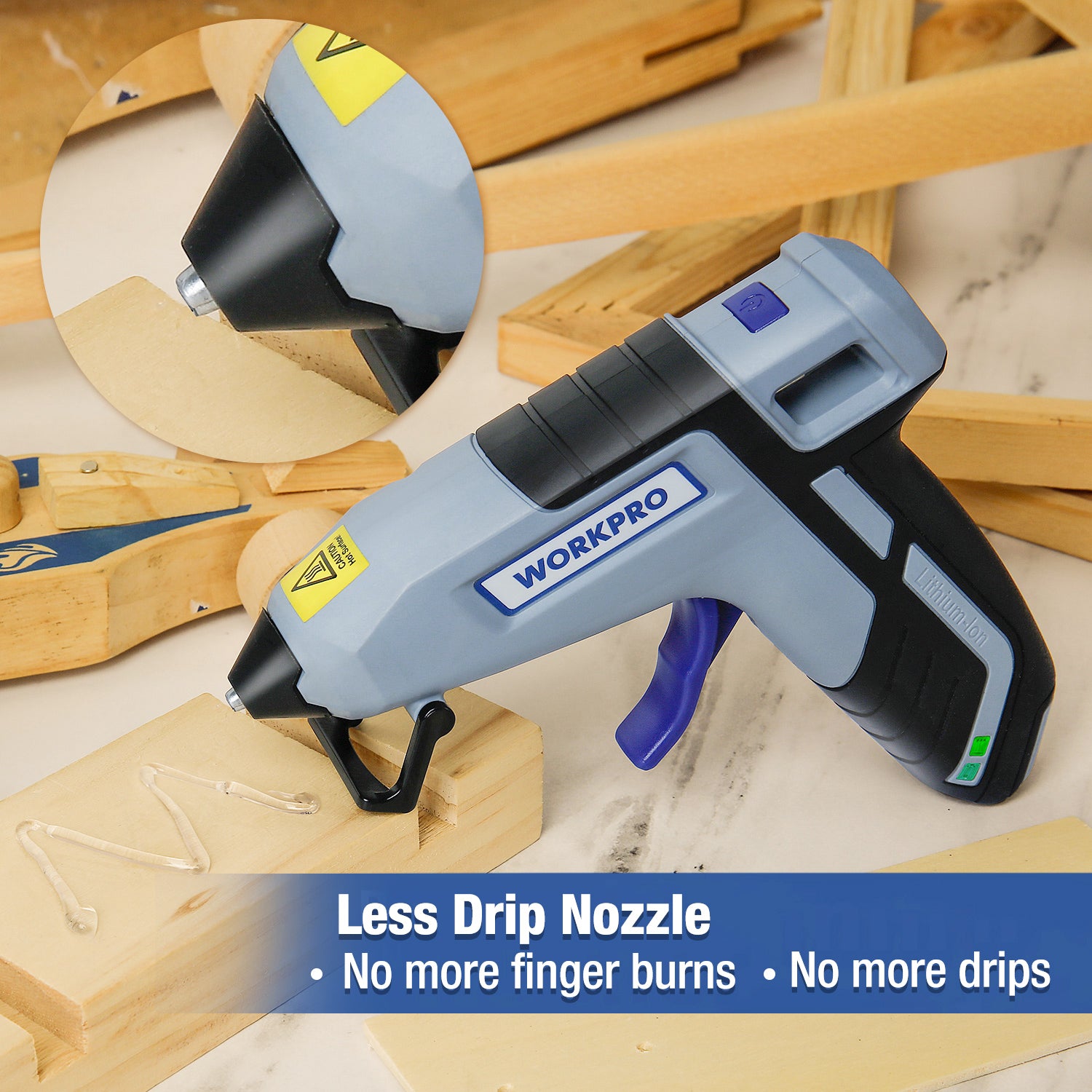 Cordless hot glue gun on craft materials, gray and black with blue trigger guard