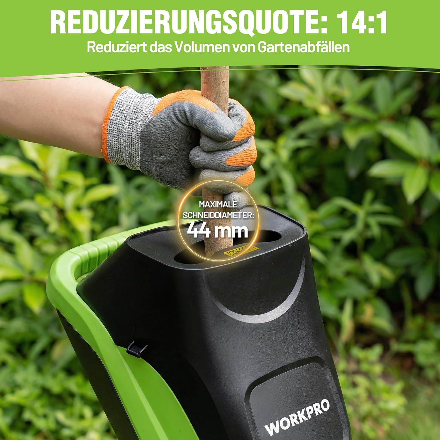 Electric garden shredder hopper being fed by gloved hand with branches