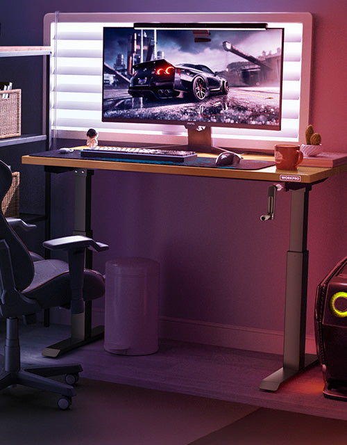 Computer desk setup with monitor showing a racing game, lit keyboard, and chair in a dim room