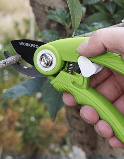 Hand holding green pruning tool with spring blade, innovation and quality shown near garden plants